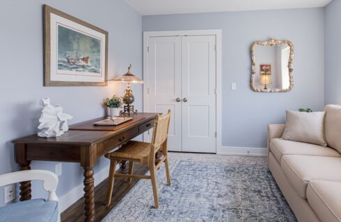 Bedroom's sitting are with light blue walls, hardwood flooring, cream upholstered sofa and wooden desk with chair